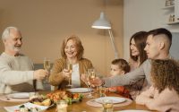 A joyful family toasts together over a festive dinner with champagne indoors.