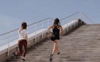 Two women running up stairs outdoors, embodying fitness and wellness.